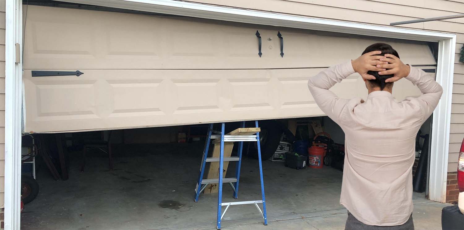 Garage doors repair - Broken door and man holding is head in desperation